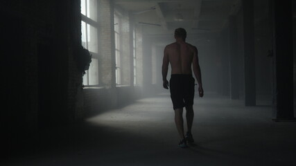 Fototapeta na wymiar Muscular athlete walking in crossfit gym. Man going in sport club for training