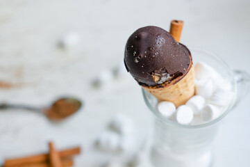 chocolate ice cream in a cone in a glass with marshmallows on a white background. Sweet dessert on...