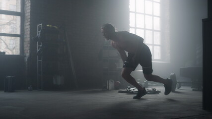Fototapeta na wymiar Athlete standing on start position in crossfit gym. Man running in loft building