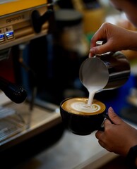 Fototapeta na wymiar barista pouring milk into cup of coffee 