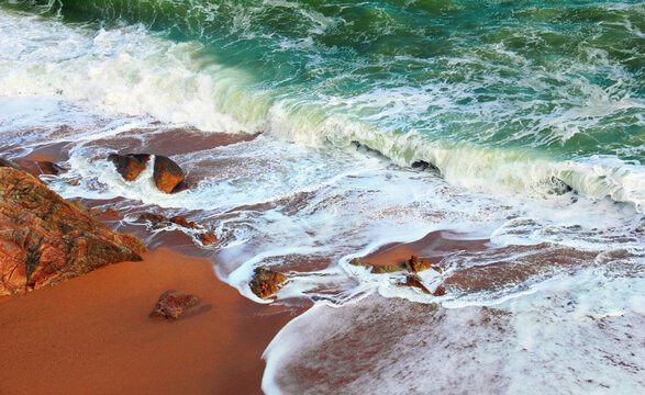 Facinating nature scene - raging sea, green water, white surf foam, rocks and wet sand. Stormy weather in Costa Brava, Mediterranean sea, Calella beach, Province of Barcelona, Catalonia, Spain