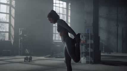Fototapeta na wymiar Sportswoman stretching legs before training. Girl warming muscles in gym