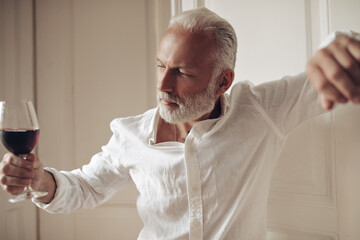 Cool man in white shirt holds wine glass. Charming adult guy in fashionable clothes posing with drink on white background