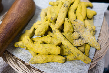 Yellow turmeric powder and dry roots on white background.