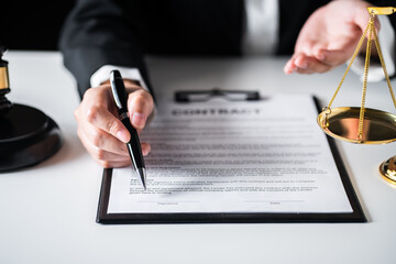 Close up of view Business woman or Female lawyer recommend to sign contract paper with Judge gavel, brass scale on a desk at law firm office, law, and justice concept.