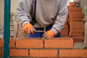 Construction worker building a brick wall. Man bricklaying. Mason laying bricks.