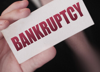 Bankruptcy on a card. Businessman holding a card with word Bankruptcy. Crisis business closing debts loss financial fiasko concept