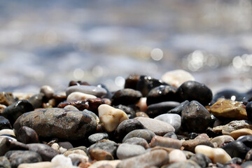 Pebble stones on blurred background of sea waves. Summer vacation concept