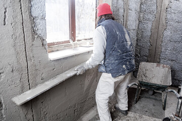 Fototapeta premium Real construction worker working on a wall inside the new house.
