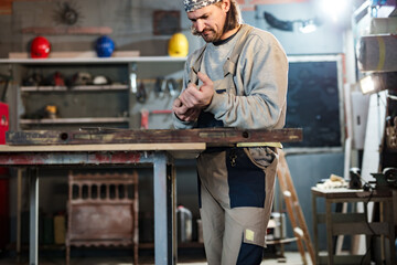 Male carpenter working on old wood in a retro vintage workshop.