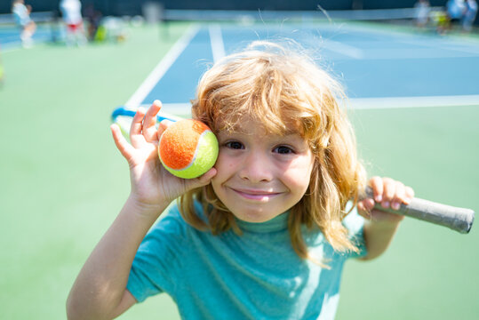 Cute Kid Boy With Tennis Racket On Court At The Tennis Competition. Funny Kids Face.