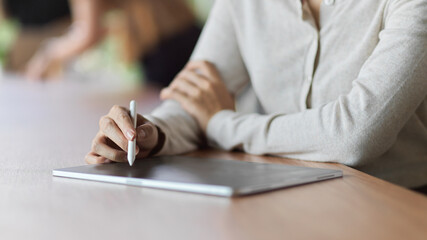 Close-up view of female using tablet with stylus pen to take notes while meeting