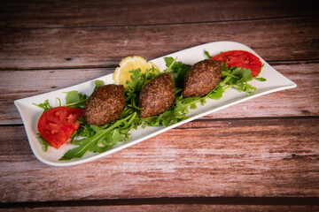 Traditional kebbe and pita bread on big round plate in lebanese restaurant. High quality photo