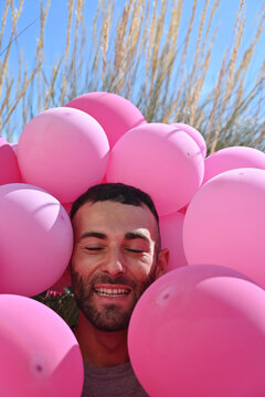Vertical shot of a Caucasian man with pink balloons in Italy