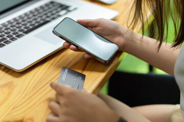 Close up female transferring money via smartphone and credit card, mobile phone with blank empty screen