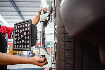 Auto service mechanic installing wheel alignment sensor on tire during vehicle suspension alignment...