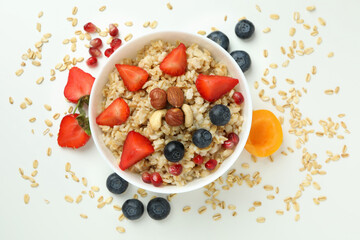 Bowl of oatmeal and ingredients on white background