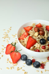 Bowl of oatmeal and ingredients on white background