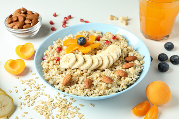 Bowl of oatmeal and ingredients on white background