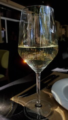 Blurred sun flare in transparent wine glass on tabletop. Glassware for white wine at table setting. Alcohol drink tasting