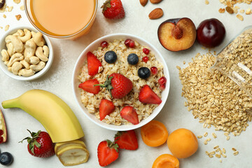 Bowl of oatmeal and ingredients for cooking on white background