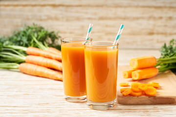 Fresh carrot juice in glasses on a  white wooden table, selective focus.