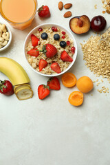 Bowl of oatmeal and ingredients for cooking on white background