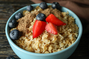 Bowl of oatmeal and kitchen towel on wooden table