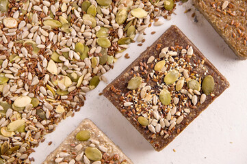 A lot of different halva on a white background next to the ingredients, seeds on a white background. View from above. Healthy sweets