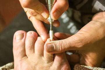Apparatus pedicure with an electric machine in a beauty salon. Professional manicurist polishing the nail plate, cuticle. Women's feet close up. A pedicure apparatus with a drill. Nail care concept.