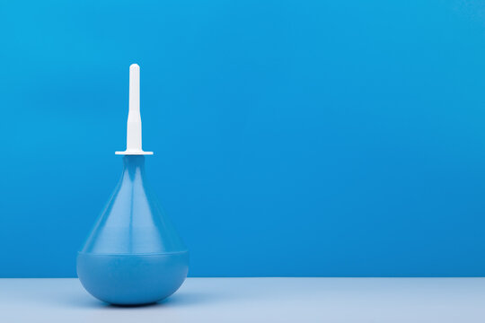Blue enema on white table against blue background with copy space. Close up of blue syringe, concept of medical treatment