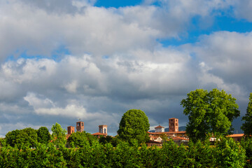Fototapeta na wymiar Lucca charming historic center skyline with beautiful clouds and medieval towers rises above surrounding anciet walls park trees