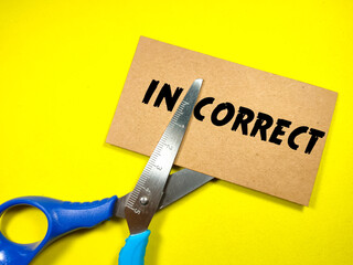 Education concept.Text IN CORRECT on brown card with scissors on yellow background.