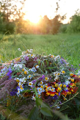 wreath of wild flower on sunny meadow. Summer Solstice Day, Midsummer concept. floral traditional decor. pagan witch traditions, wiccan symbol and rituals