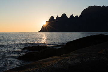 Midnight sun hitting scenic cliffs of Tungeneset on Senja island in northern Norway at a warm calm summer night