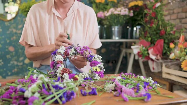 Crop woman creating flower wreath in florist shop