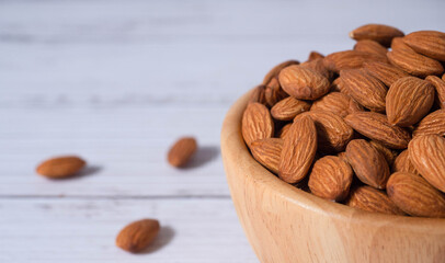Tasty organic peeled almond snack in wooden bowl on white wooden background with copy space.Close up heap almonds shelled nut .Healthy food concept.