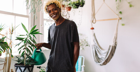 Happy young man taking care of his pot plant