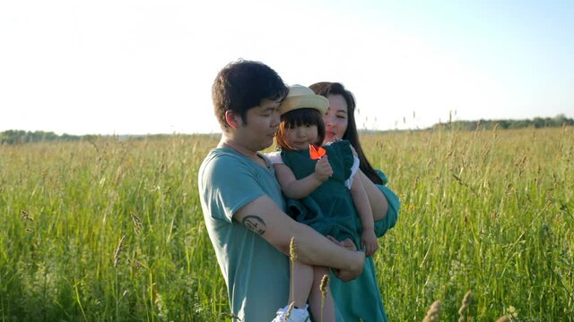 Korean family with their daughter go to the field in the grass at sunset