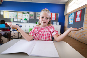 Fototapeta premium Portrait of caucasian girl sitting on her desk in the class at elementary school