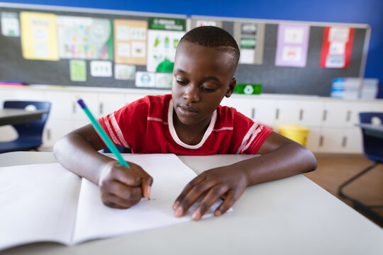 African american boy studying while sitting on his desk in the class at elementary school