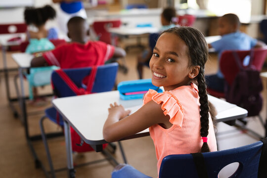 Portrait of african american girl smiling while sitting in the class at elementary school