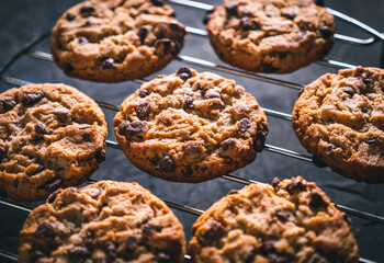 Homemade chocolate chip cookies on a metal rack on a dark table. Ready to eat.