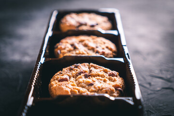 Open chocolate chip cookies package on a dark table. Ready to eat.