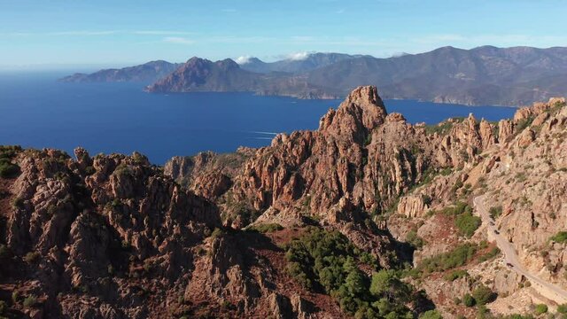 Panoramic aerial view of rocky red mountain, canyon with sea in the background in a summer sunny day. Characteristic rock mountains, blue sea, blue sky, sunny day.Corsica Calanques.