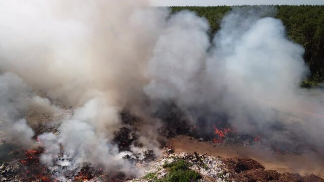 Clouds of smoke exhaling from burning trash at garbage dump. Polluting air with toxic gases from burning plastic, rubber and other trash