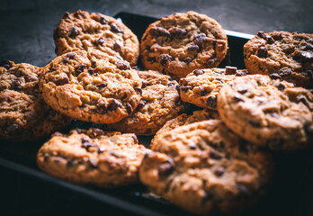 Homemade chocolate chip cookies on a black square plate on a dark table. Ready to eat.
