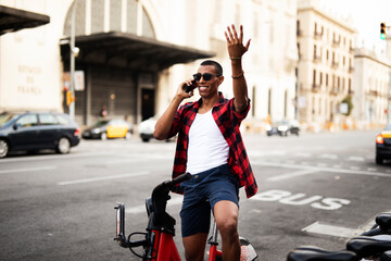 Portrait of handsome african man using electric bike in the city. Happy young man using the phone.