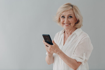 Elderly caucasian old aged woman portrait gray haired portrait enjoying using mobile phone messaging