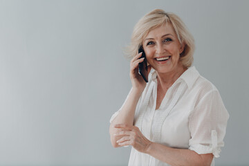 Elderly caucasian old aged woman portrait gray haired portrait enjoying speaking mobile phone